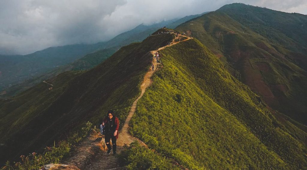 A girl trekking over a dirt road over Dinosaur Spine of Ta Xua in the very early morning