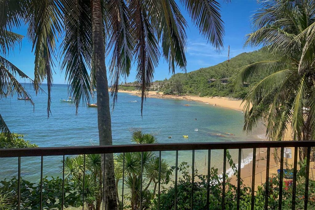 Golden sandy stretch of Bai Xep Beach framed by mountains and palm trees, with calm waters ideal for swimming and relaxing.