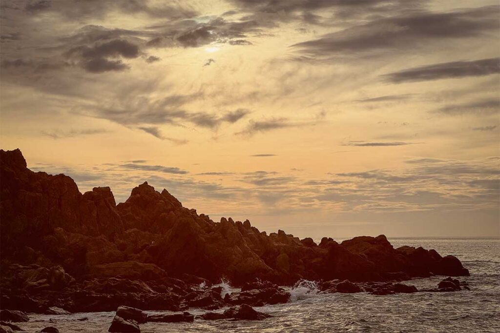Sunrise at Bai Xep Beach – Dramatic coastal rocks lit by early morning sun, with waves crashing against the rugged shoreline.