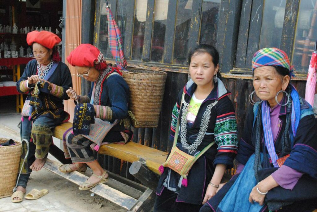 ethnic minority woman sitting in traditional dresses on a bench at a local village near Sapa