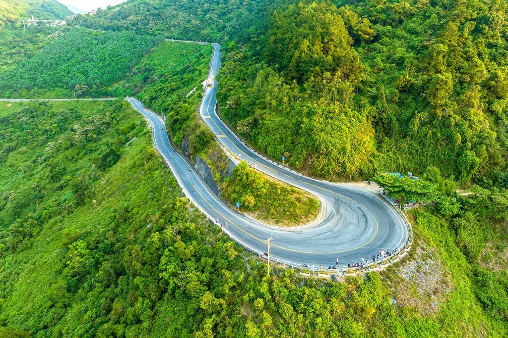 Big Hairpin Curve on Hai Van Pass – A dramatic aerial view of the famous hairpin curve on Hai Van Pass, surrounded by lush green hills and winding roads.