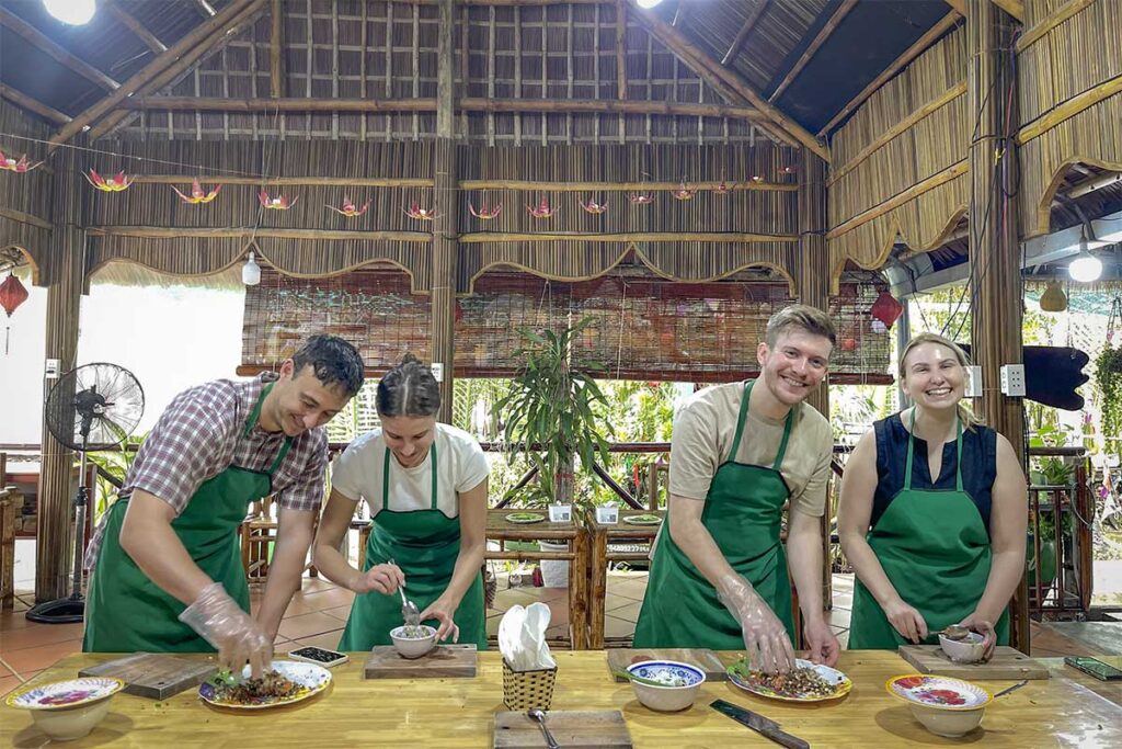 Travelers preparing local dishes in a hands-on Hoi An cooking class