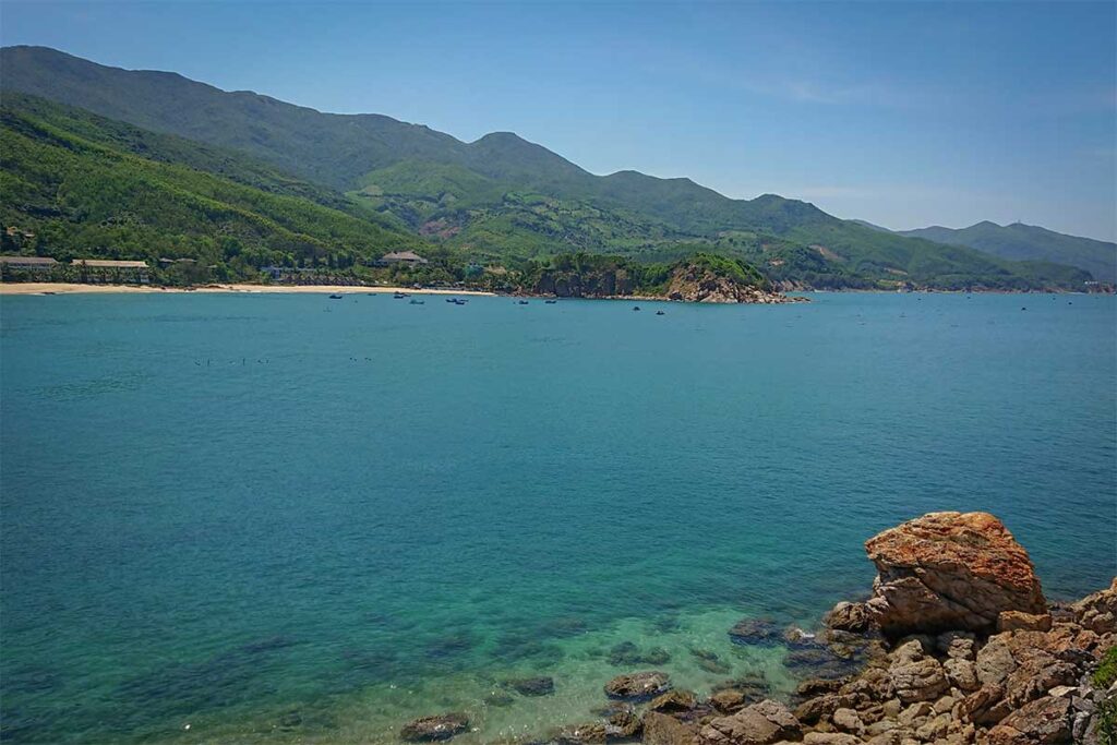 Wide coastal view from Hon Ngang Island showing Bai Xep bay and surrounding mountains with calm blue waters.
