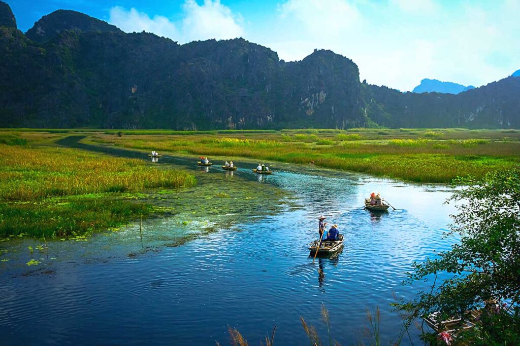 Two boats floating on the wetland area of Van Long Nature Reserve.