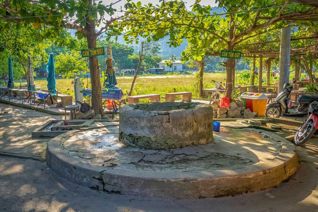 Ancient Cham Well on Cham Island shaded by trees, a centuries-old water source linked to local legend and daily village life.