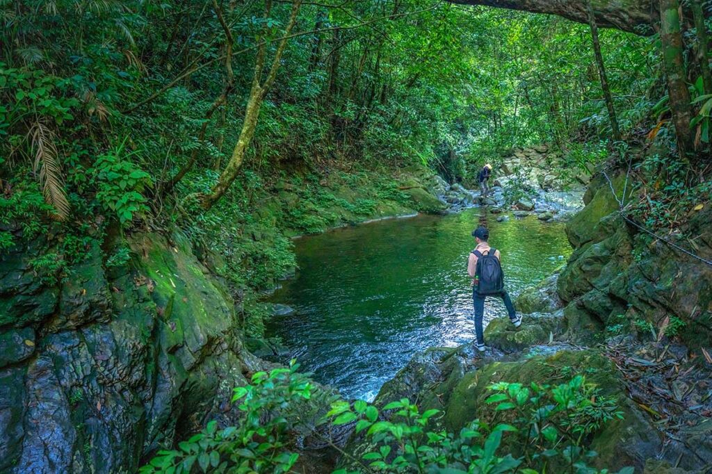 A man standing at a small lake during the five lake trekking in Bach Ma National Park