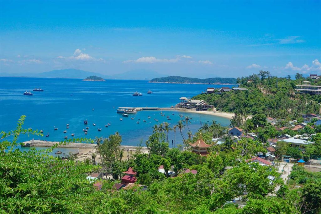 View over Bai Huong fishing village on Cham Island with moored boats, temples, and blue coastal waters.