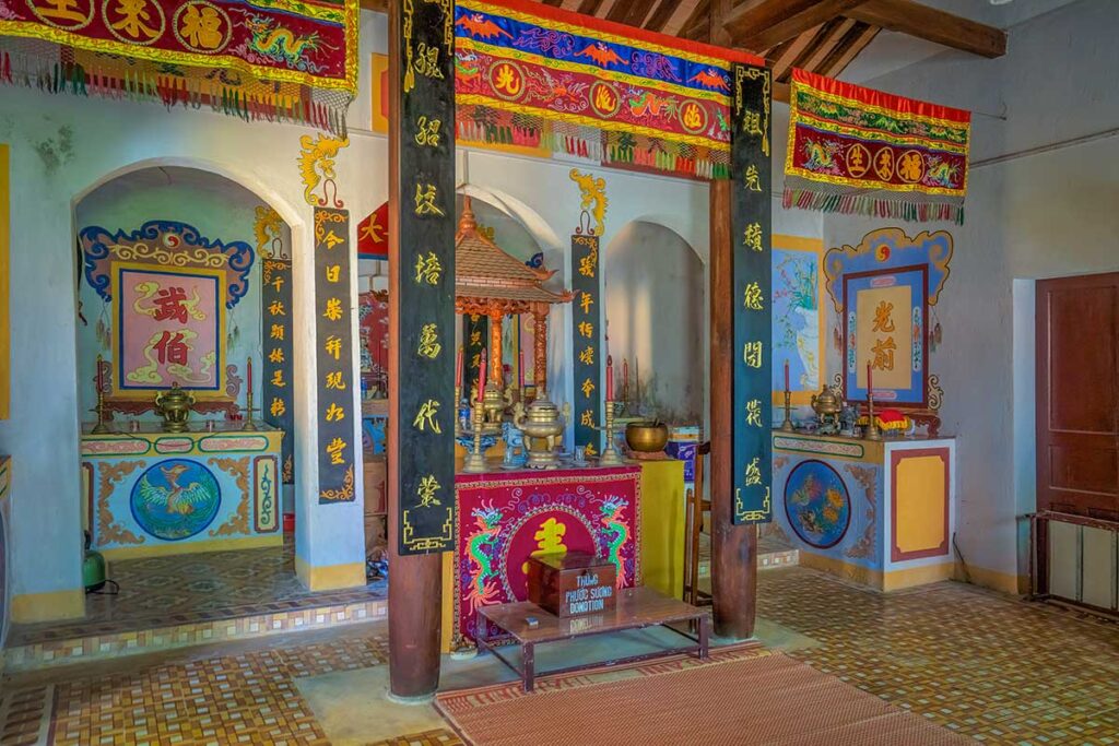Colorful interior of Hai Tang Pagoda on Cham Island, with ornate altars, dragon motifs, and centuries-old worship banners.