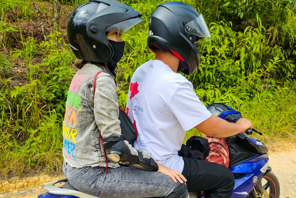 A tourist riding on the back of a motorbike in Ha Giang, driven by a local guide - also called Easy Riders