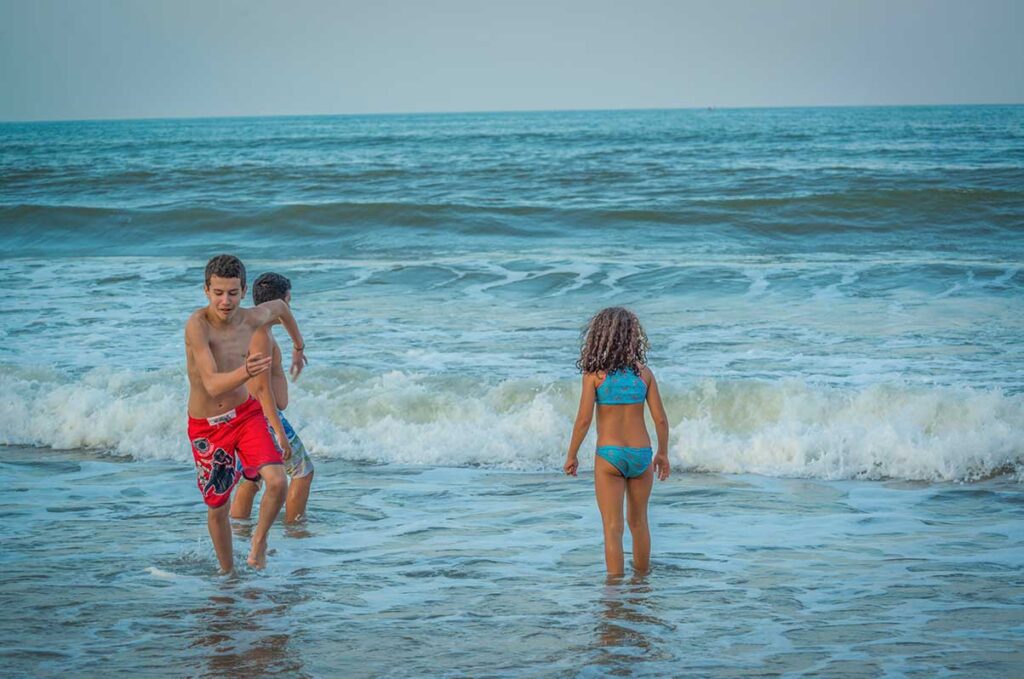 Hoi An with kids – children playing and swimming in the waves at An Bang Beach during a family beach day