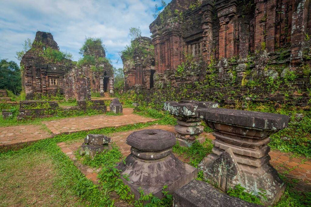 Cham temple ruins at My Son Sanctuary surrounded by green hills and forest, showing the peaceful valley setting in Central Vietnam