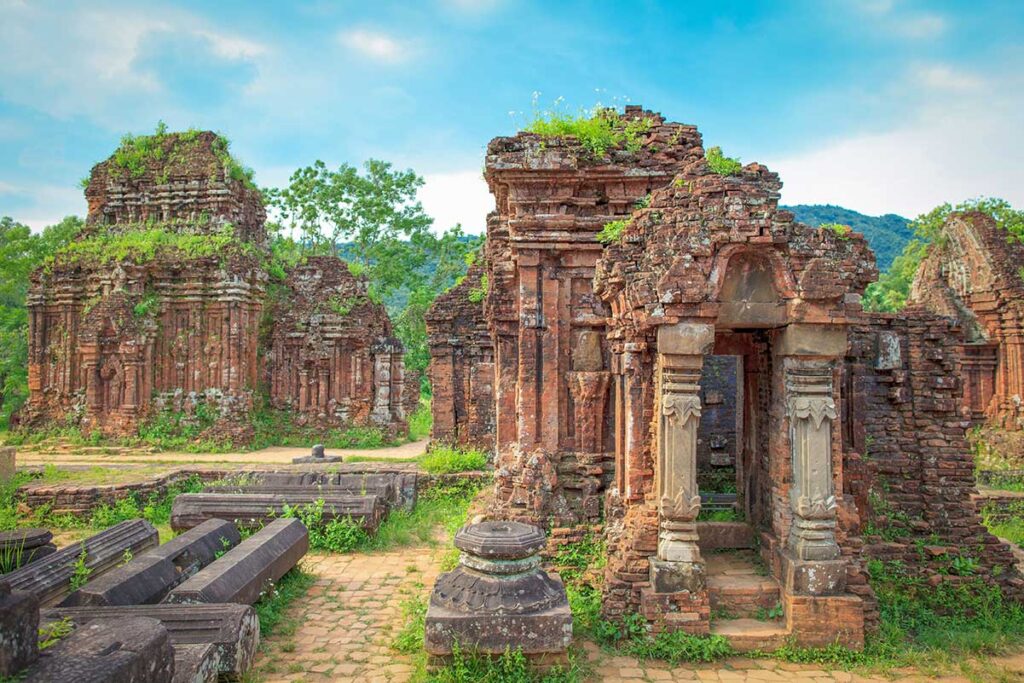 Ancient Cham brick temples at My Son Sanctuary overgrown with moss and framed by misty mountains after a tropical rain