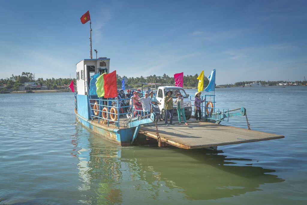 Local ferry crossing to Tam Hai Island, carrying motorbikes and villagers across the calm Truong Giang River in Quang Nam Province.