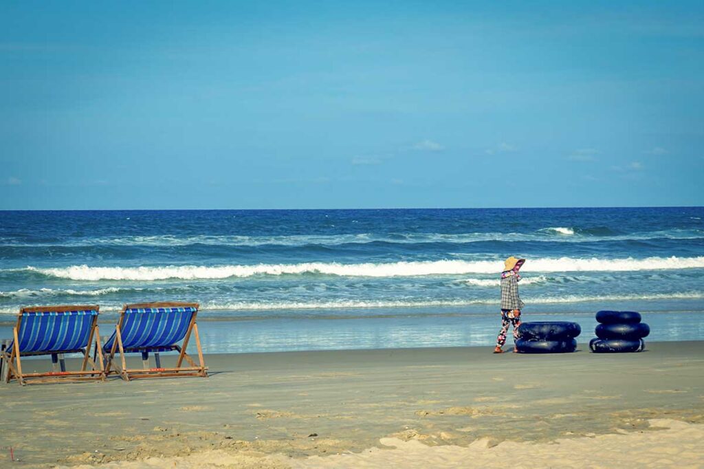 Quiet morning at Tan Thanh Beach Hoi An with striped beach chairs and gentle ocean waves