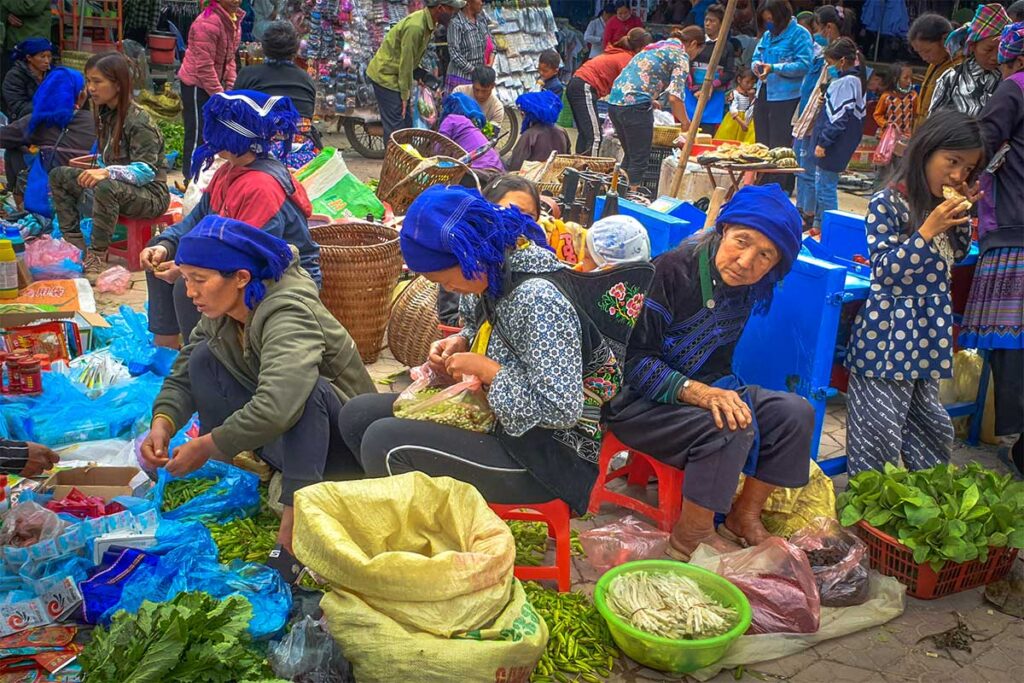 Local ethnic woman in traditional clothes are standing sitting on the floor selling food at the local Y Ty Market