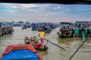 Early morning activity at Cai Rang Floating Market with small sampan serving food and drinks between rows of larger trading boats.