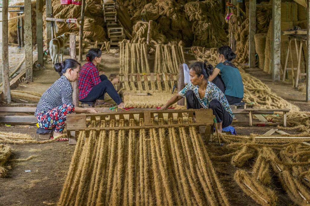 ocal women weaving coir mats from coconut fiber in a traditional workshop in Ben Tre, Mekong Delta, Vietnam.