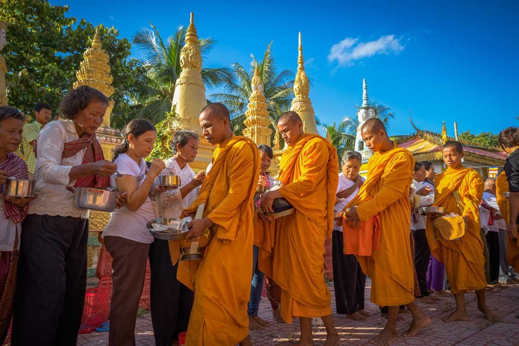 Khmer monks collecting alms in An Giang – Morning ceremony at a Khmer pagoda with locals offering food in southern Vietnam.