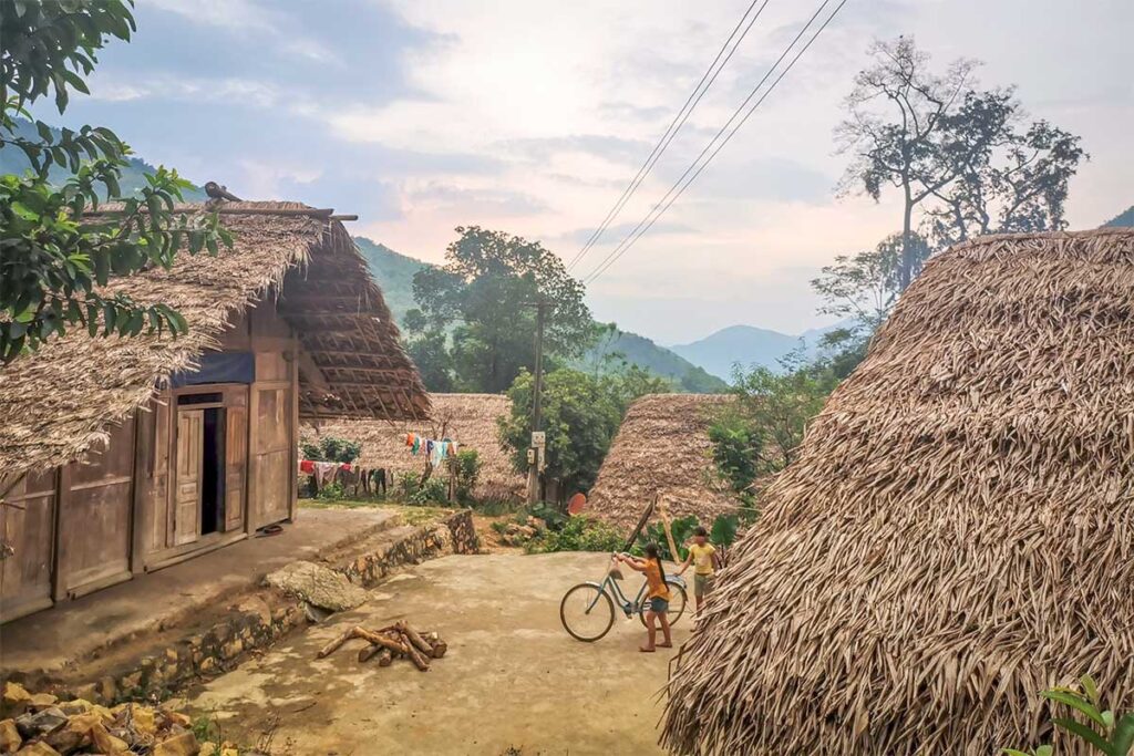 Traditional stilt houses uses as local homestays with palm leaves and dirt roads in a very rural setting nearby Hoa Binh Lake