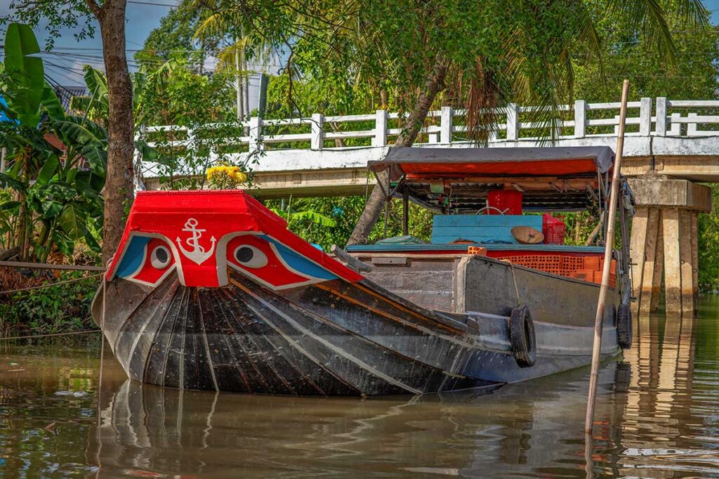 Traditional Mekong boat with painted eyes docked on a canal in Sa Dec, Dong Thap