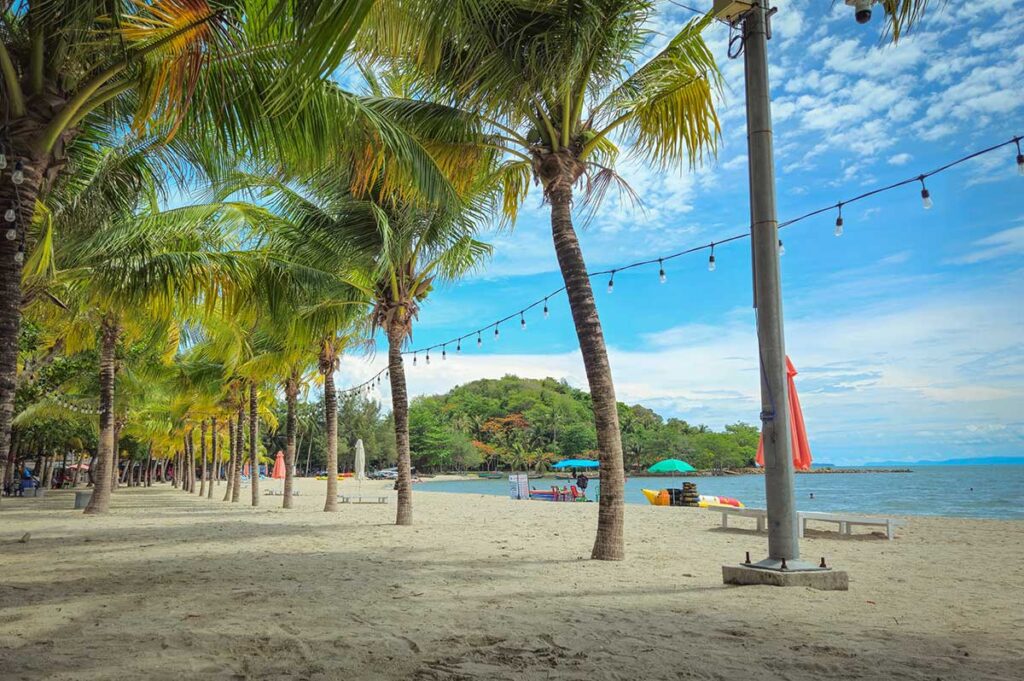 Palm-lined Mui Nai Beach in Ha Tien with umbrellas, cafés, and calm sea views.