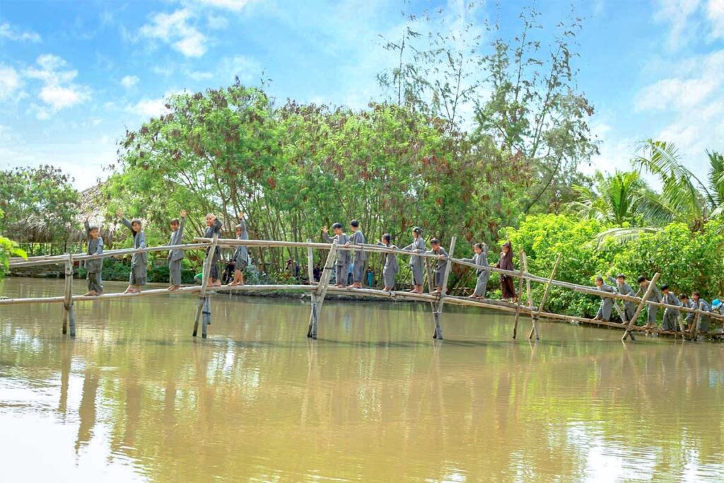 Children crossing a traditional monkey bridge at Vam Ho Bird Sanctuary in Ben Tre