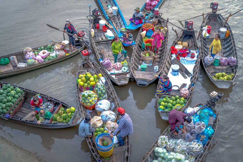 Cluster of wooden boats filled with pomelos, watermelons, and produce at Phong Dien Floating Market in Can Tho.
