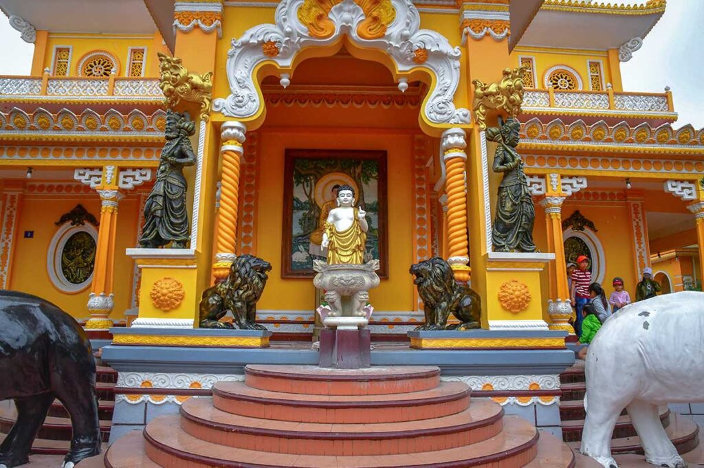 Front entrance of Tay An Pagoda at the base of Sam Mountain, with Buddha statue and colorful yellow façade.