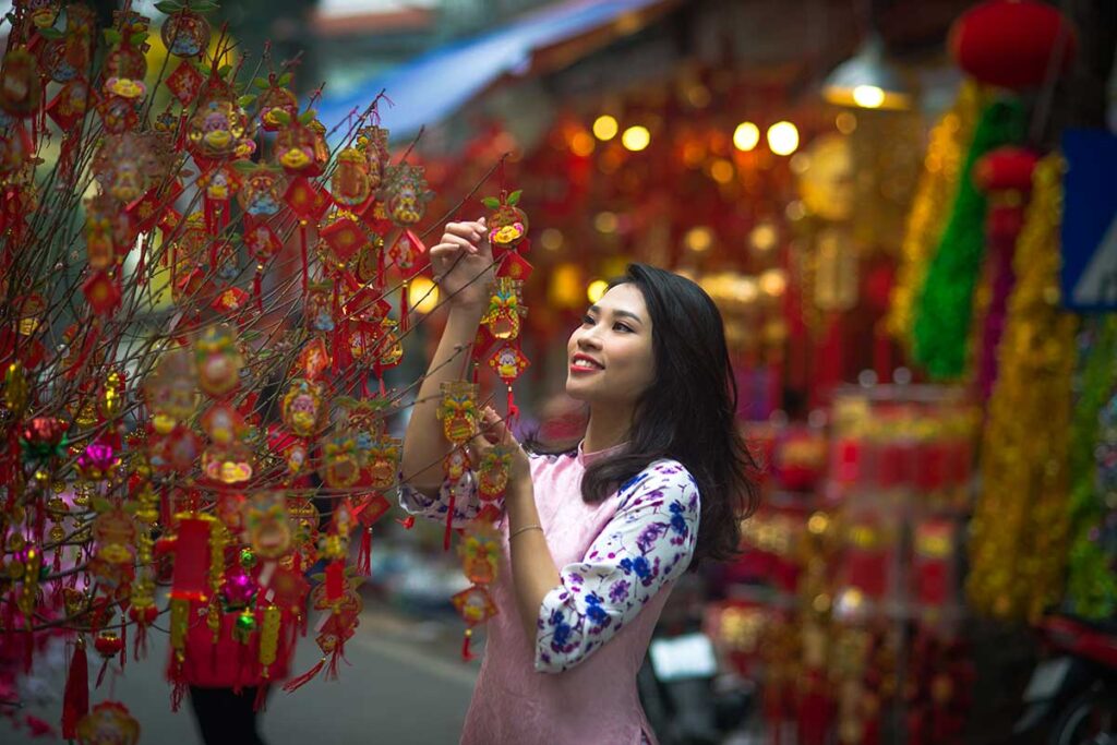 Vietnamese girl shopping decorations for Vietnamese New Year Tet