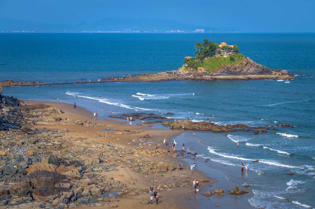 View of Hon Ba Island with temple and the coastline that is connected by rock path during low tide