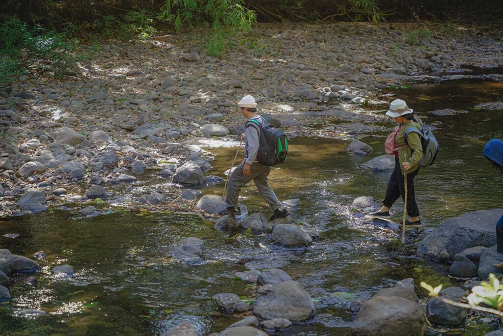 Two tourists crossing a stream inside Bu Gia Map National Park