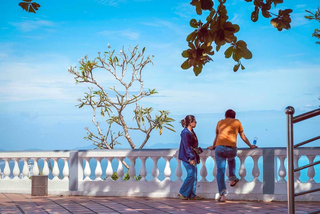 Two people at the fence at the base of Vung Tau Lighthouse enjoying the view