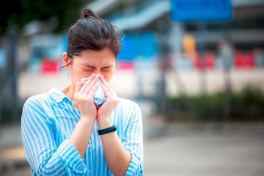 Woman sneezing due to allergies while traveling in Vietnam.