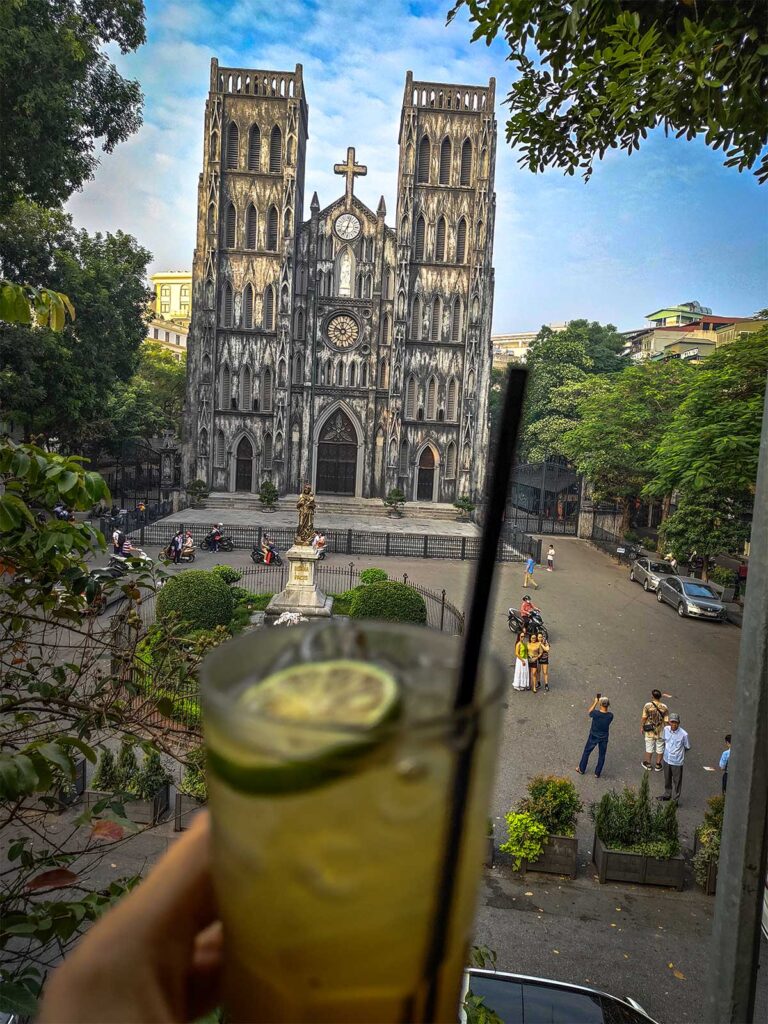 St. Joseph's Cathedral View from Cafe: A charming cafe table overlooks the intricate details and stained glass windows of St. Joseph's Cathedral's side facade in Hanoi. (St. Joseph’s Cathedral)