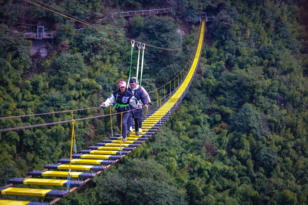 Cloud Bridge where two people are walking over a 
swing bridge at Cau Kinh Rong May amusement park