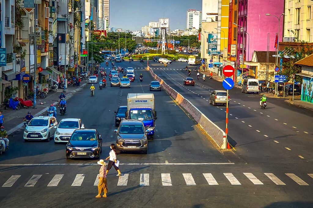 Two people crossing the road at a pedestrian crossing in Vietnam, guided by traffic lights.