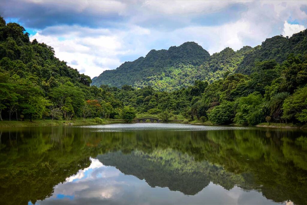 Cuc Phuong National Park Lake: A serene lake formed by the Red River Delta shimmers in the sunlight within the lush Cuc Phuong National Park