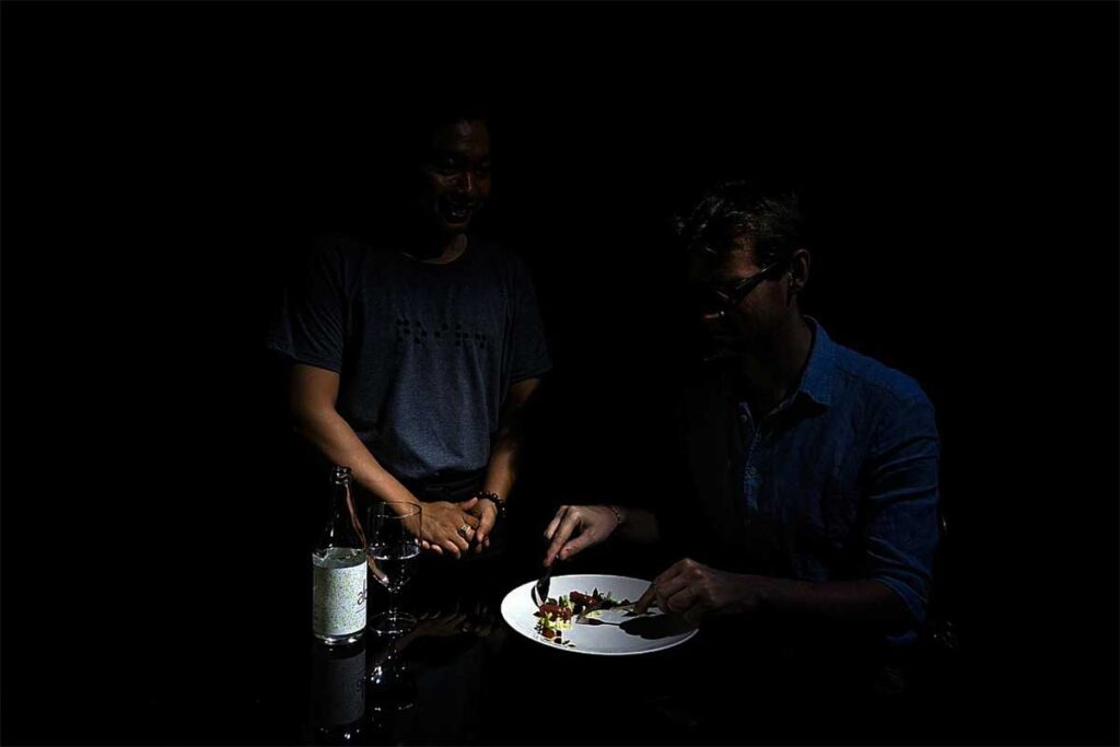 Noir. Dining in the Dark: A dimly lit photo captures the unique sensory experience of dining in the dark at Noir. restaurant in Hanoi. (unique dining in Hanoi)