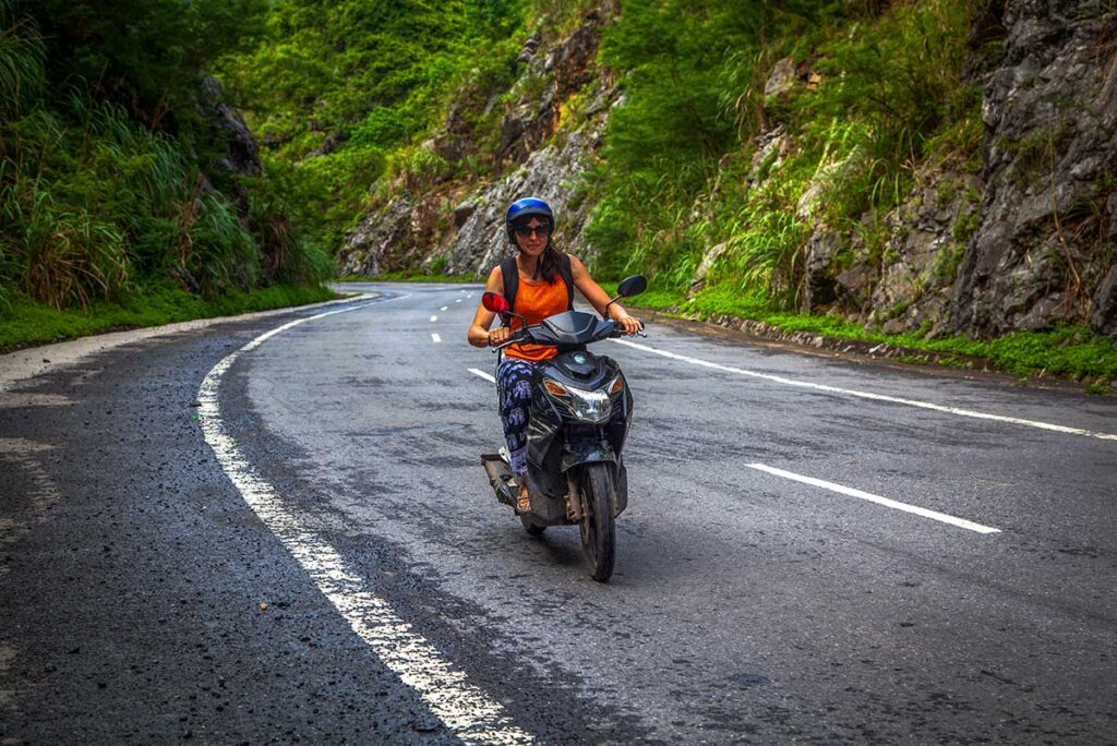 Girl riding a scooter through the scenic mountainous roads of Vietnam.