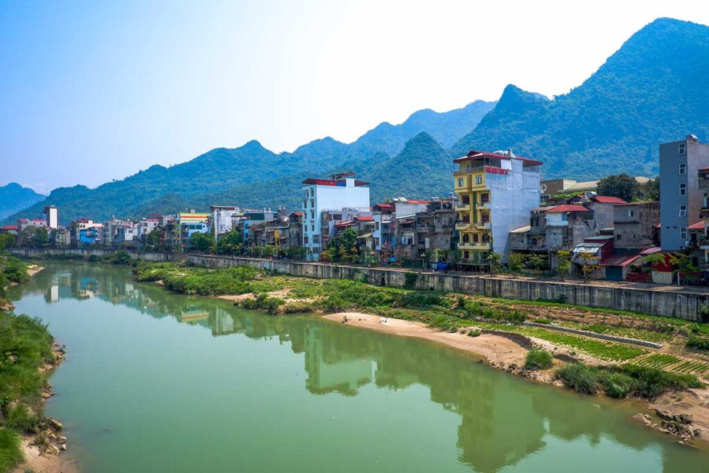 Ha Giang Cityscape: The serene river winds through Ha Giang city, with colorful houses lining its banks and mountains forming a dramatic backdrop.