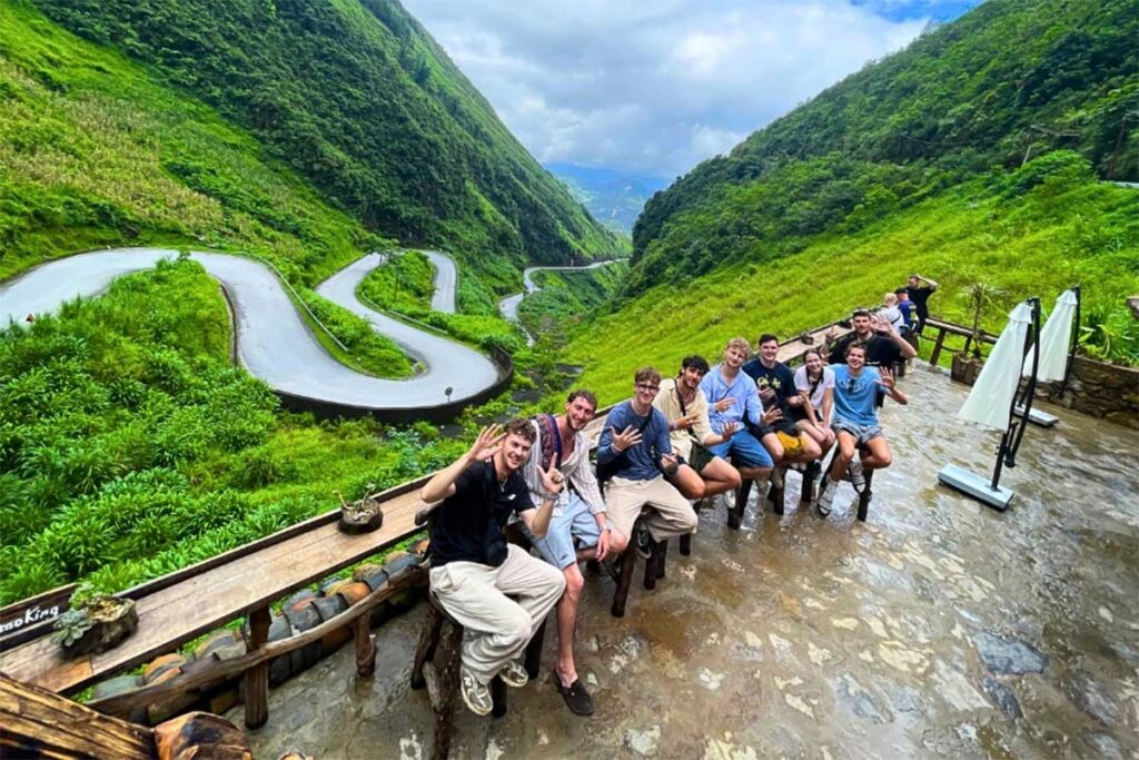 A group of backpackers in Vietnam sitting at a viewpoint of Tham Ma Pass, along the infamous Ha Giang Loop