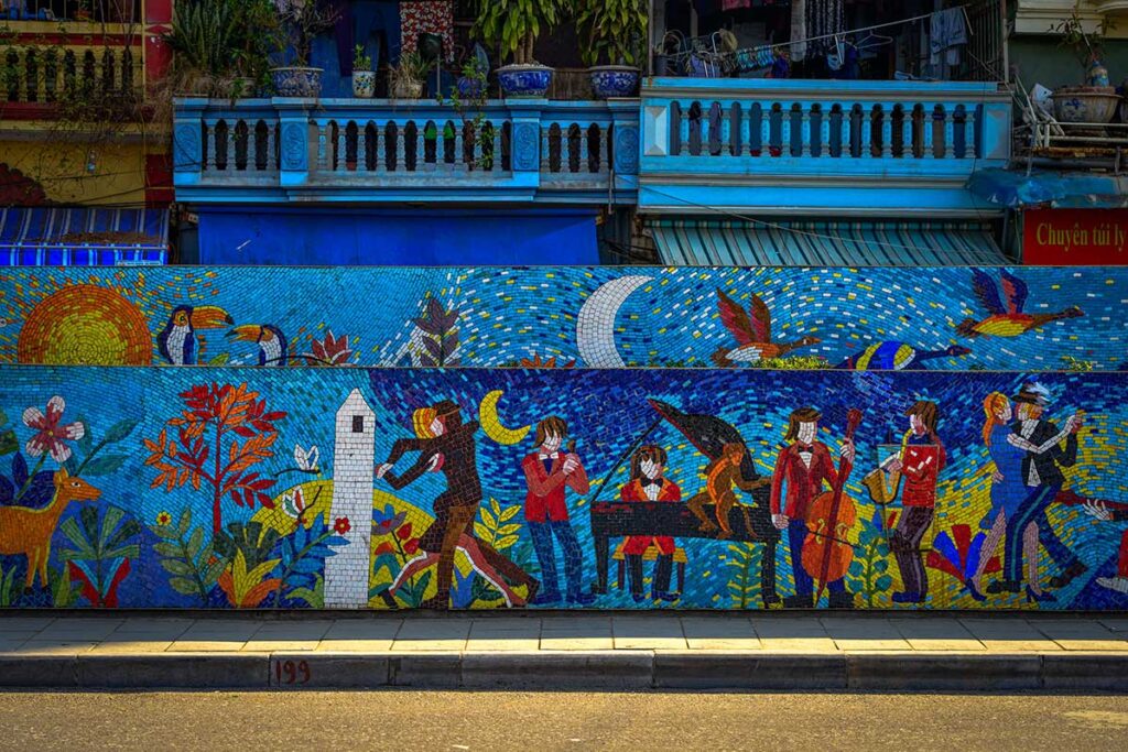 Hanoi Ceramic Mosaic Mural Music Scene: A mural on the Hanoi Ceramic Mosaic depicts musicians playing traditional instruments and people dancing, celebrating Vietnamese culture.