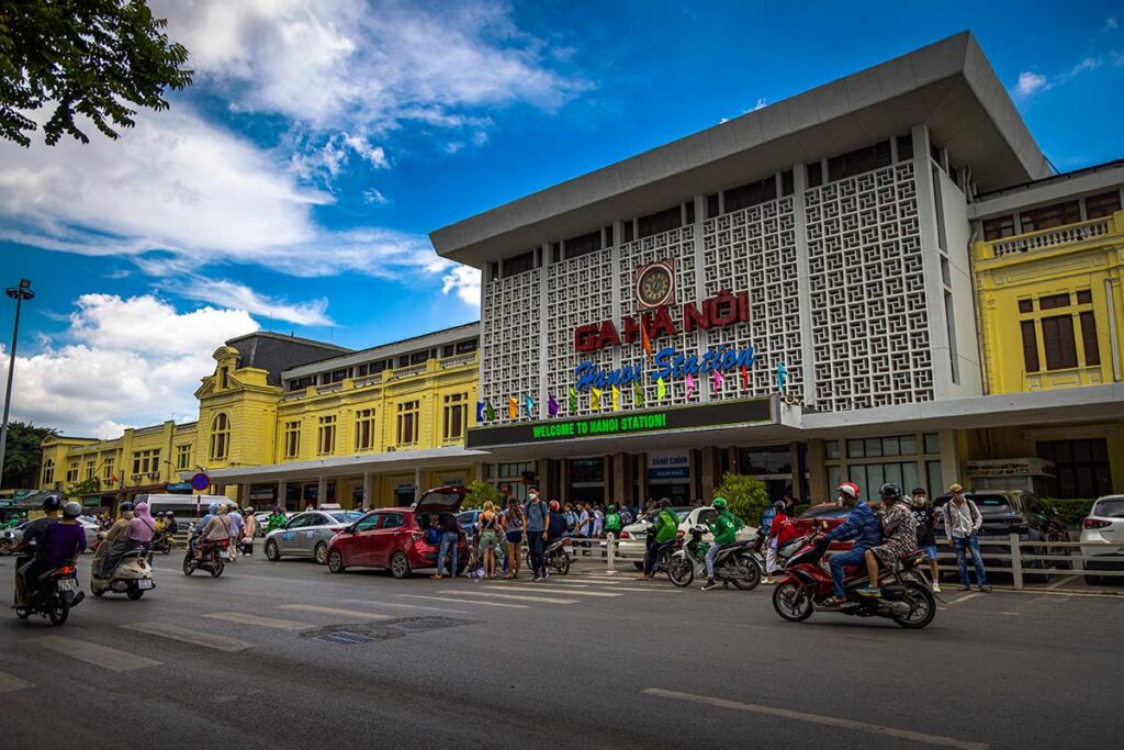 Front view of Hanoi Railway Station with busy tourists disembarking from taxis and entering the station