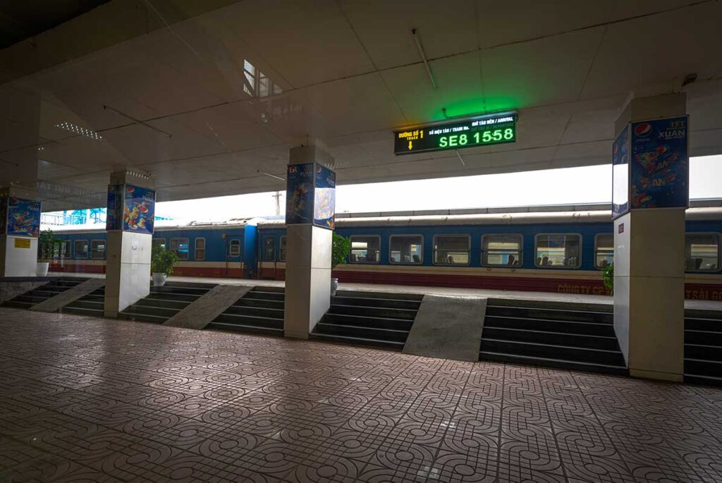 Interior of Hanoi Railway Station with a train parked on the platform, capturing the station's bustling atmosphere.