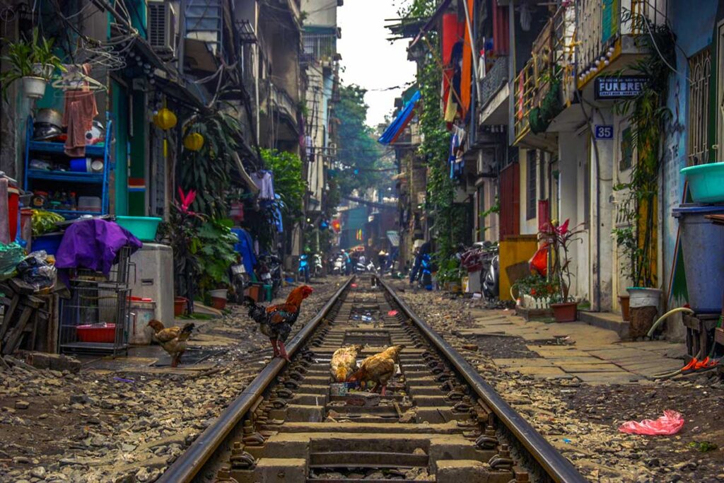 Hanoi Train Street: A train rumbles through the narrow Hanoi Train Street, passing between vibrantly colored houses.