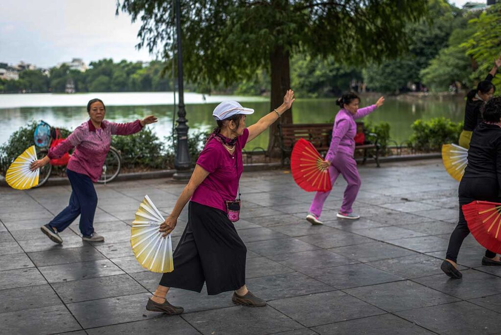 Tai Chi at Hoan Kiem Lake: A local woman practices tai chi with a graceful fan at Hoan Kiem Lake, a serene oasis in the heart of Hanoi.