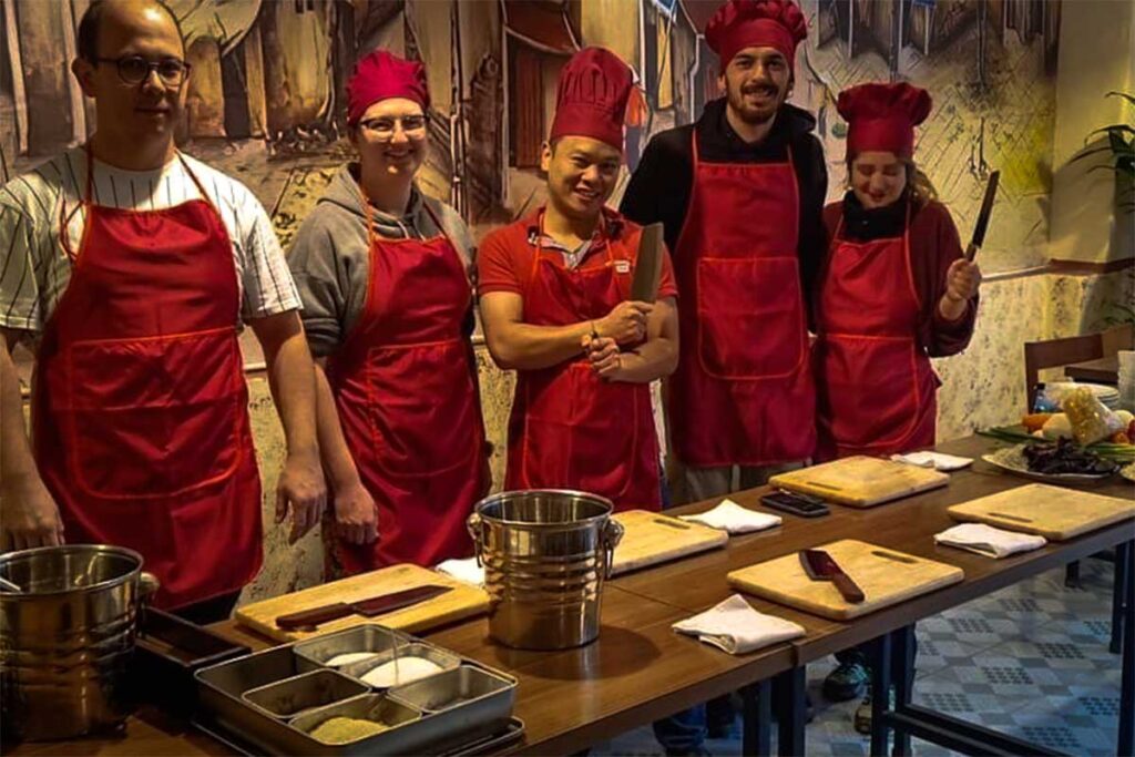 Hoang Cooking Class with Chef Hoang: Chef Hoang poses with two foreign couples, all wearing aprons and chef hats, ready to embark on a culinary adventure at Hoang Cooking Class in Hanoi.