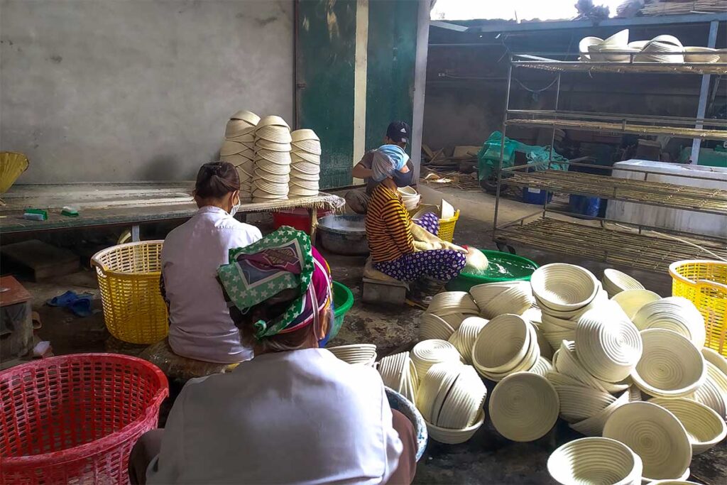 Local artisans craft intricate bamboo baskets in a workshop at Phu Vinh Bamboo Village, Vietnam.