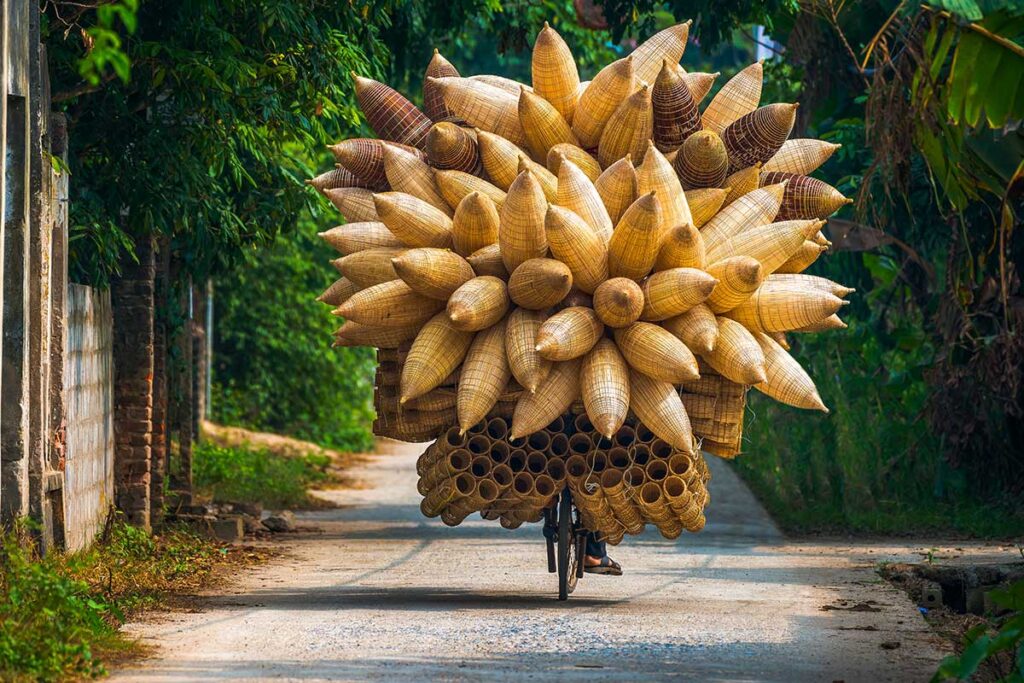 a man riding a bike full of bamboo fish traps at Thu Sy Fish Trap Craft Village