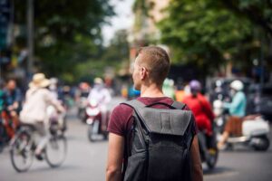 Solo male traveler navigating the busy streets of Hanoi Old Quarter with a backpack.